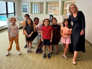 Adult with 8 first grade students smiling at the camera